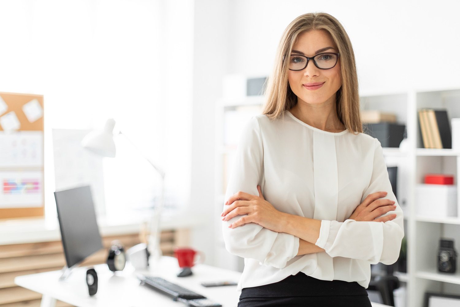 Beautiful young blonde girl in white blouse and black skirt is working in the office. photo with depth of field